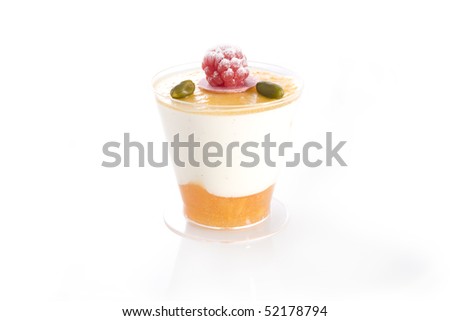 Isolated shot of Vanilla and mango mousse with raspberry and pistachio topping.