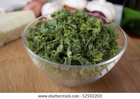 Chopped kale in clear glass bowl on cutting board