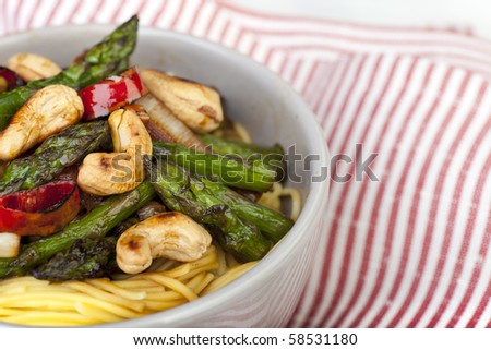 Close up of asparagus and cashew stir fry over Chinese noodles.