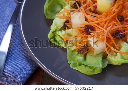 Fresh carrot salad with shredded carrots, raisins, apples and a light curry yogurt dressing on a bed of lettuce