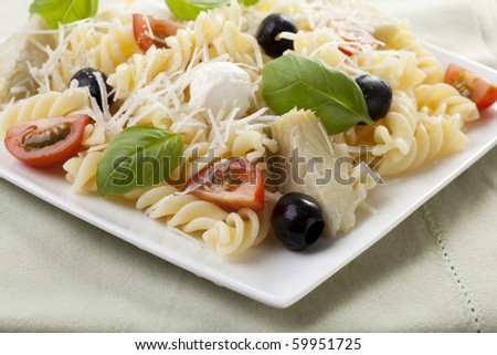 Fusilli pasta with black olives, mozzarella cheese, artichoke hearts and tomato slices, topped with fresh basil leaves.