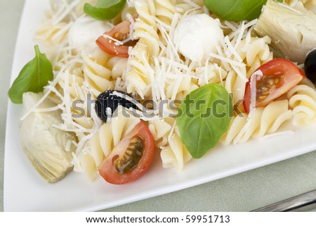 Fusilli pasta with black olives, mozzarella cheese, artichoke hearts and tomato slices, topped with fresh basil leaves.