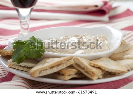Hummus plate with pita chips and cilantro garnish.
