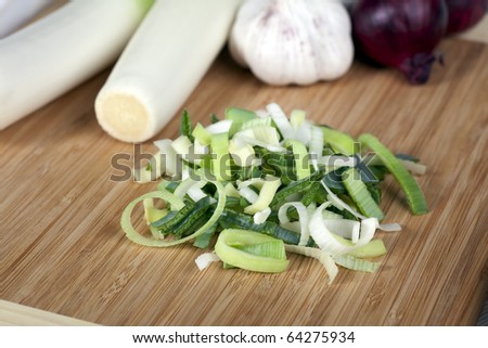 Sliced leeks with whole leeks, garlic and red onions in background.