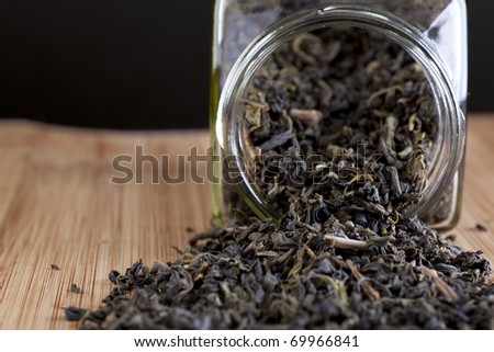 Jasmine tea leaves spilling from jar on wooden surface