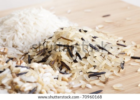 Close-up brown and wild grain rice with other varieties of rice in the background.