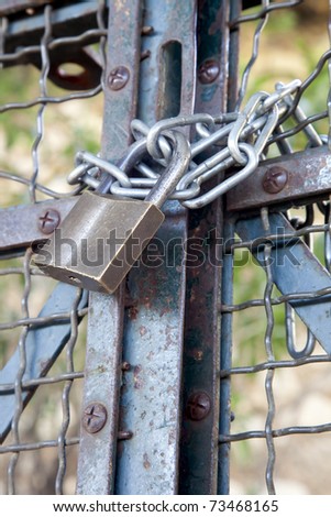Metal padlock and chain on metal gate.