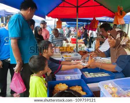 MALACCA, MALAYSIA-AUG 06: Unidentified traditional dish seller attends to a customer at Pasar Ramadan Merlimau on August 06, 2012 in Malacca, Malaysia. Muslims around the world start fasting today.