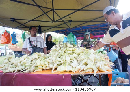 PAHANG, M'SIA-AUG 18: Unidentified traditional food seller attends to a customer at Pasar Ramadan Kuantan on August 18, 2012 in Pahang, Malaysia. Muslims around the world celebrate Aidilfitri tomorrow