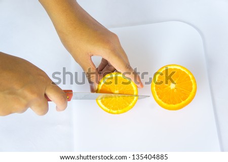 woman hand and knife cutting orange juice