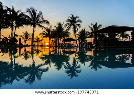 sunrise via swimming pool and silhouette coconut tree