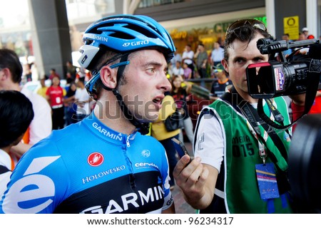MALACCA - FEBRUARY 25: Nathan Haas (AUS) being interviewed after race as teammate and tour leader David Zabriskie (behind) makes his way to the presentations, Malacca Malaysia on February 25.2012