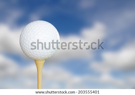 Golf ball on tee, sky blur background