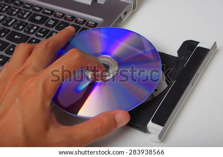 hand holding dvd insert to notebook laptop computer