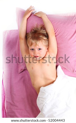 little blond boy lying stretching on pink bed