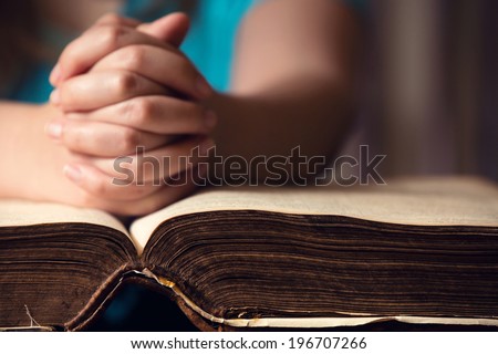 Girl praying with hands on 150 year old Bible