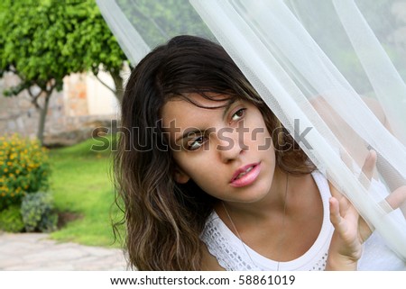 Attractive young woman hiding behind curtain veil