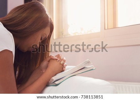 Girl Praying With her Hands Folded On The Bible