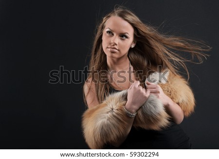 Photography of a girl in the fur that poses a stream of air ea black background