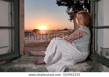Woman in the window of an old train station during the sunset