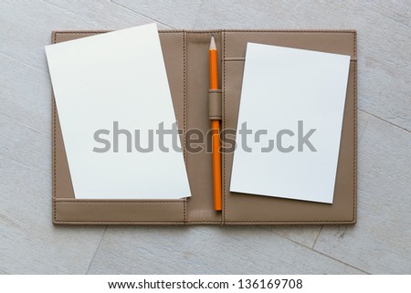 White paper and Orange Pencil on Brown Leather Bound Book