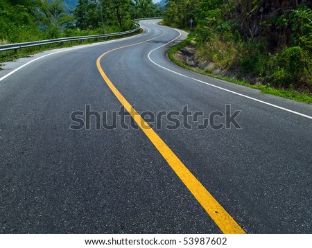The road curves up the mountain. Line yellow and white road.