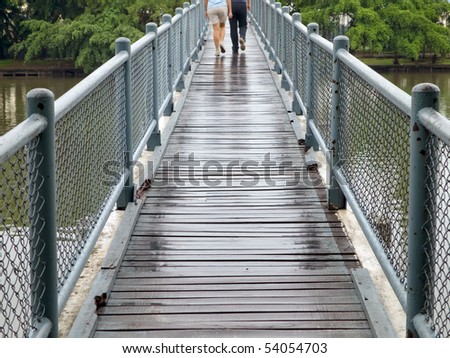 Two people walk across the bridge in the rain drizzle