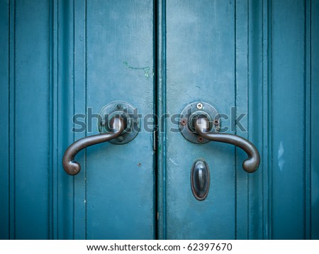 Door handles with an old double door painted with blue