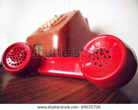 Old red telephone on wood table and white wall