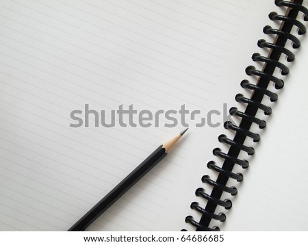 Black pencil on open white paper note book top view