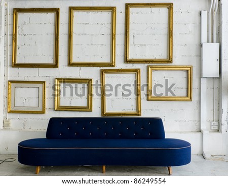 Long blue fabric sofa and gold picture frame on white wall