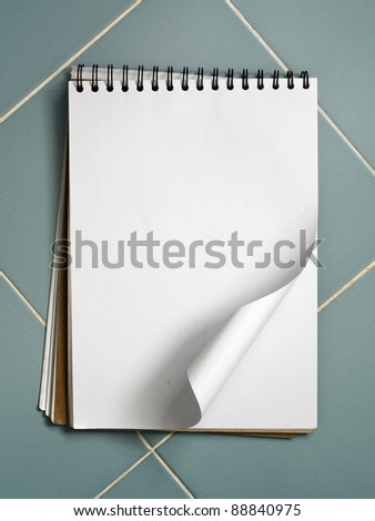 Blank white sketch book on blue ceramic wall