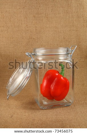 Red pepper in open jar on jute background