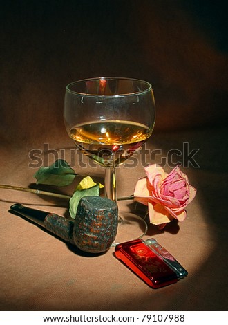 Romantic still life with glass of cognac and tobacco pipe on brown background
