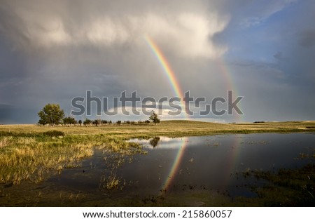 Storm Clouds Saskatchewan with rainbow reflection in water