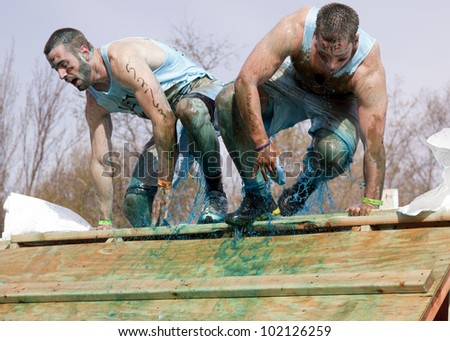 POCONO MANOR, PA - APR 28: Two men emerge from a tank filled with water and ice at Tough Mudder on April 28, 2012 in Pocono Manor, PA. The course is designed by British Special Forces.