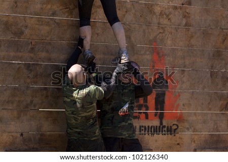 POCONO MANOR, PA - APR 29: An entrant gets help to get up and over the Berlin Walls obstacle at Tough Mudder on April 29, 2012 in Pocono Manor, PA.  The course is designed by British Special Forces.
