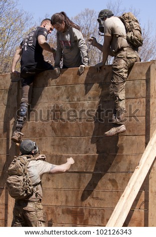 POCONO MANOR, PA - APR 29: A participant gets help up and over the Berlin Walls obstacle at Tough Mudder on April 29, 2012 in Pocono Manor, PA.  The course is designed by British Special Forces.
