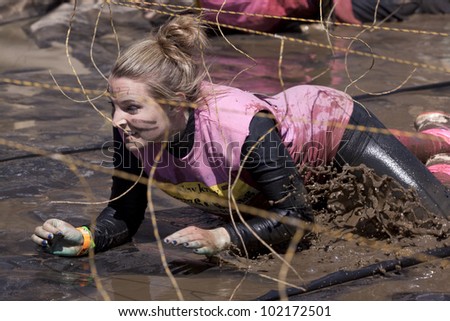 POCONO MANOR, PA - APR 29: A woman crawls through water under electrified wires at Tough Mudder on April 29, 2012 in Pocono Manor, Pennsylvania. The course is designed by British Royal troops.
