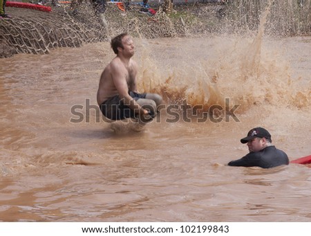 POCONO MANOR, PA - APR 28: A man splashes into water from the Walk the Plank obstacle at Tough Mudder on April 28, 2012 in Pocono Manor, Pennsylvania. The course is designed by British Royal troops.