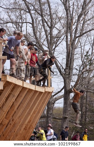 POCONO MANOR, PA - APR 28: Participants jump off the Walk the Plank obstacle into water at Tough Mudder on April 28, 2012 in Pocono Manor, Pennsylvania. The course is designed by British Royal troops.