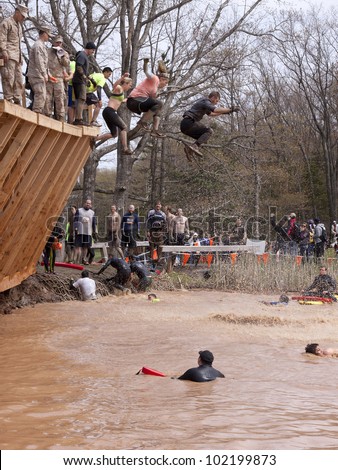POCONO MANOR, PA - APR 28: Participants jump off the Walk the Plank obstacle into water at Tough Mudder on April 28, 2012 in Pocono Manor, Pennsylvania. The course is designed by British Royal troops.