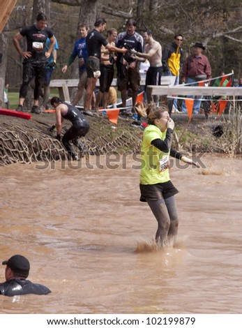 POCONO MANOR, PA - APR 28: A woman splashes into water from the Walk the Plank obstacle at Tough Mudder on April 28, 2012 in Pocono Manor, Pennsylvania. The course is designed by British Royal troops.