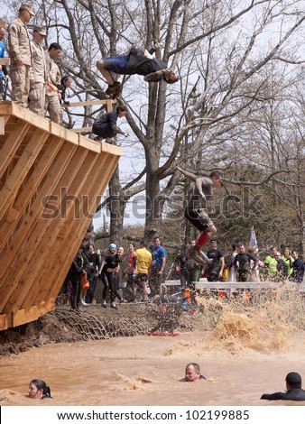 POCONO MANOR, PA - APR 28: A man does a flip off the Walk the Plank obstacle into water at Tough Mudder on April 28, 2012 in Pocono Manor, Pennsylvania. The course is designed by British Royal troops.
