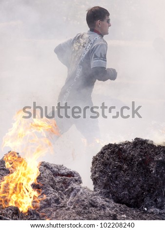 POCONO MANOR, PA - APR 28: A man runs through the Fire Walker obstacle at Tough Mudder on April 28, 2012 in Pocono Manor, Pennsylvania. The course is designed by British Royal troops.