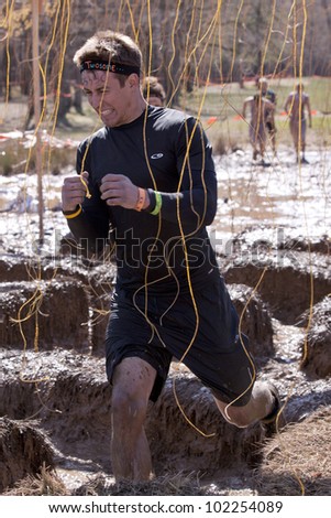 POCONO MANOR, PA - APR 29: A man runs through an obstacle with electrified wires at Tough Mudder on April 29, 2012 in Pocono Manor, Pennsylvania. The course is designed by British Royal troops.
