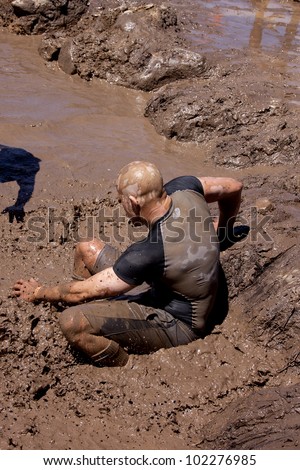 POCONO MANOR, PA - APR 29: A man slides into a pit of mud and water at Tough Mudder on April 29, 2012 in Pocono Manor, Pennsylvania. The course is designed by British Royal troops.