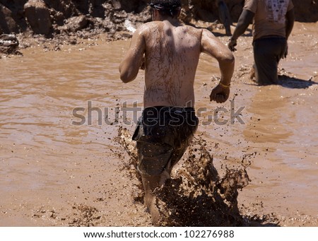 POCONO MANOR, PA - APR 29: A man runs through a pit of mud and water at Tough Mudder on April 29, 2012 in Pocono Manor, Pennsylvania. The course is designed by British Royal troops.