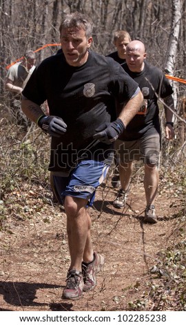 POCONO MANOR, PA - APR 29: A group of men run on a trail through the woods at Tough Mudder on April 29, 2012 in Pocono Manor, Pennsylvania. The course is designed by British Royal troops.
