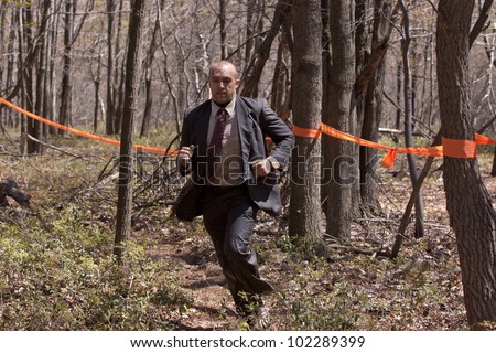 POCONO MANOR, PA - APR 29: A man in a business suit runs on a trail through the woods at Tough Mudder on April 29, 2012 in Pocono Manor, Pennsylvania. The course is designed by British Royal troops.